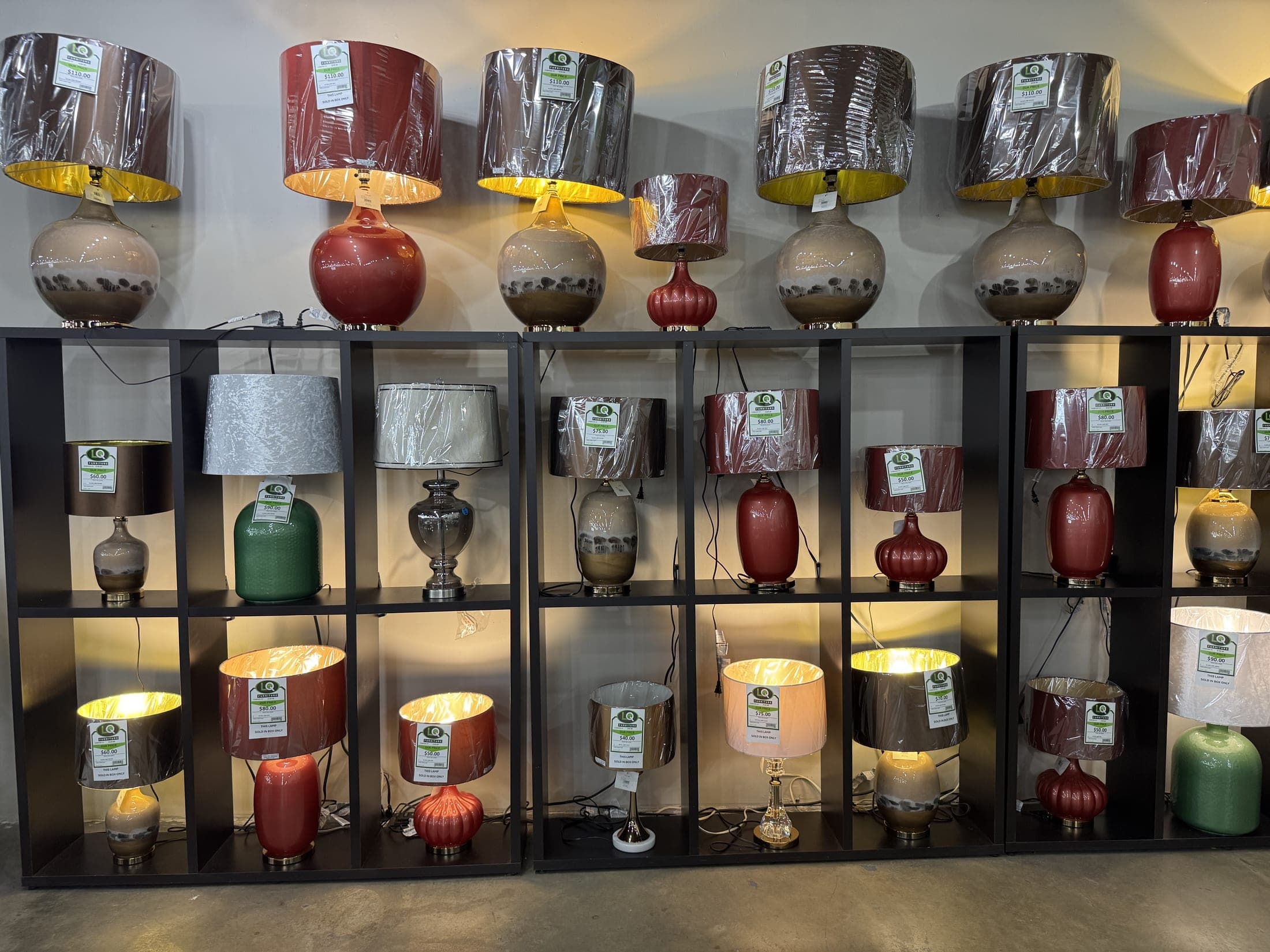 The lamp wall at LQ Furniture, shelves of lit table lamps in every color