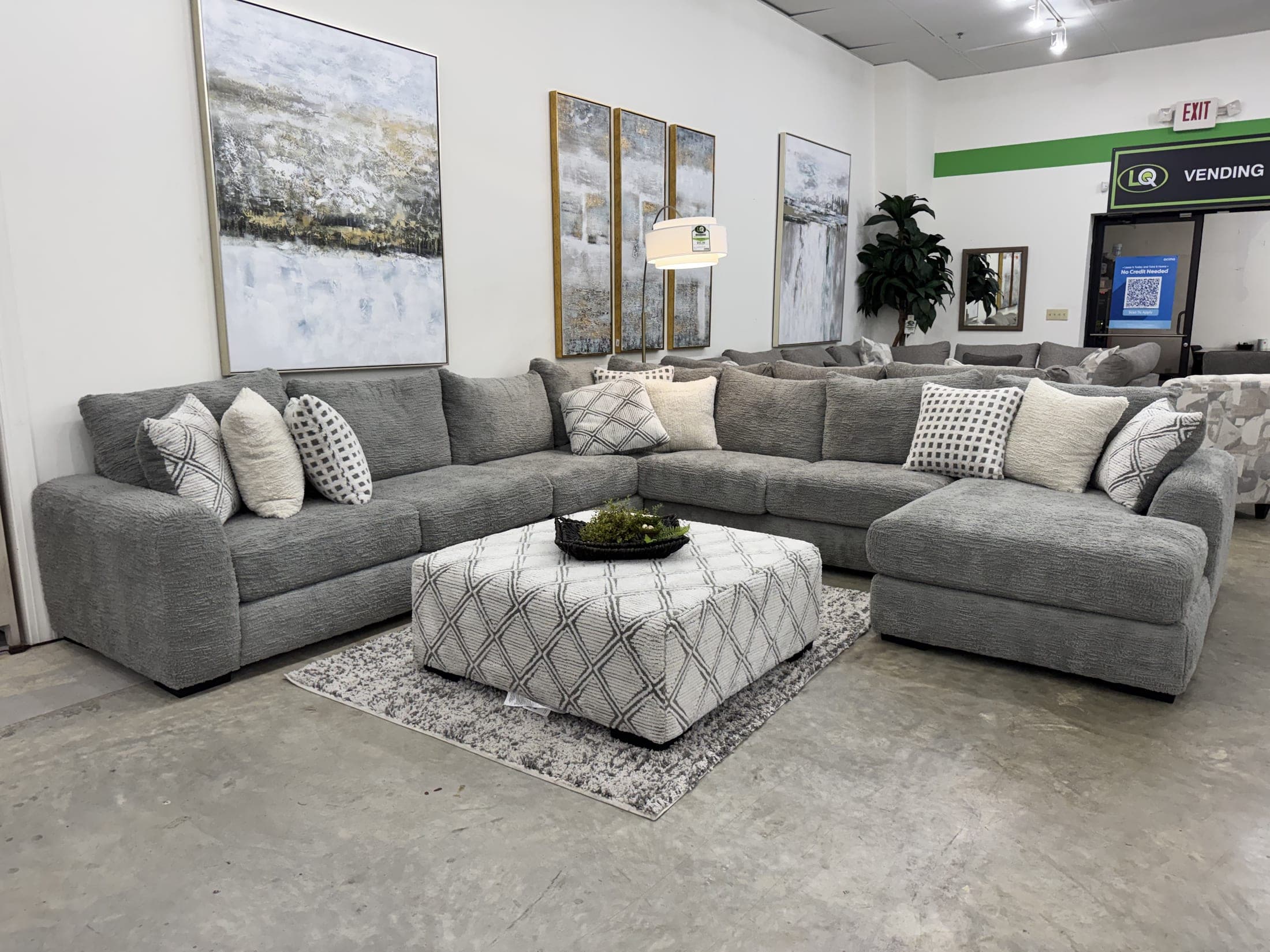 Gray sectional with patterned pillows and a tufted ottoman
