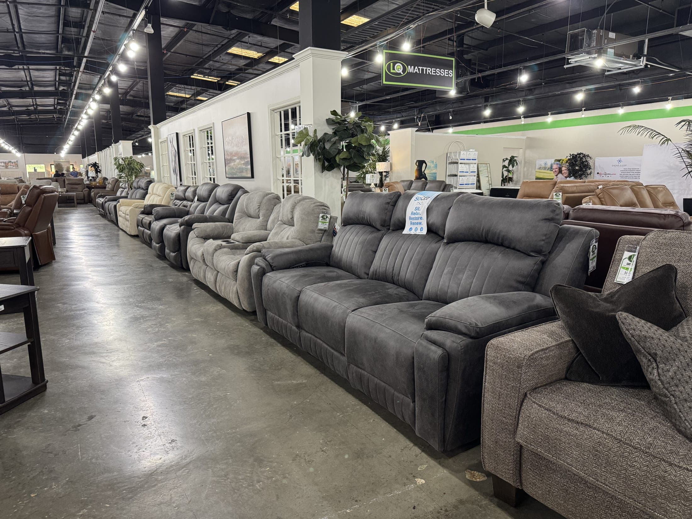 Rows of gray reclining sofas down a warehouse aisle at LQ Furniture