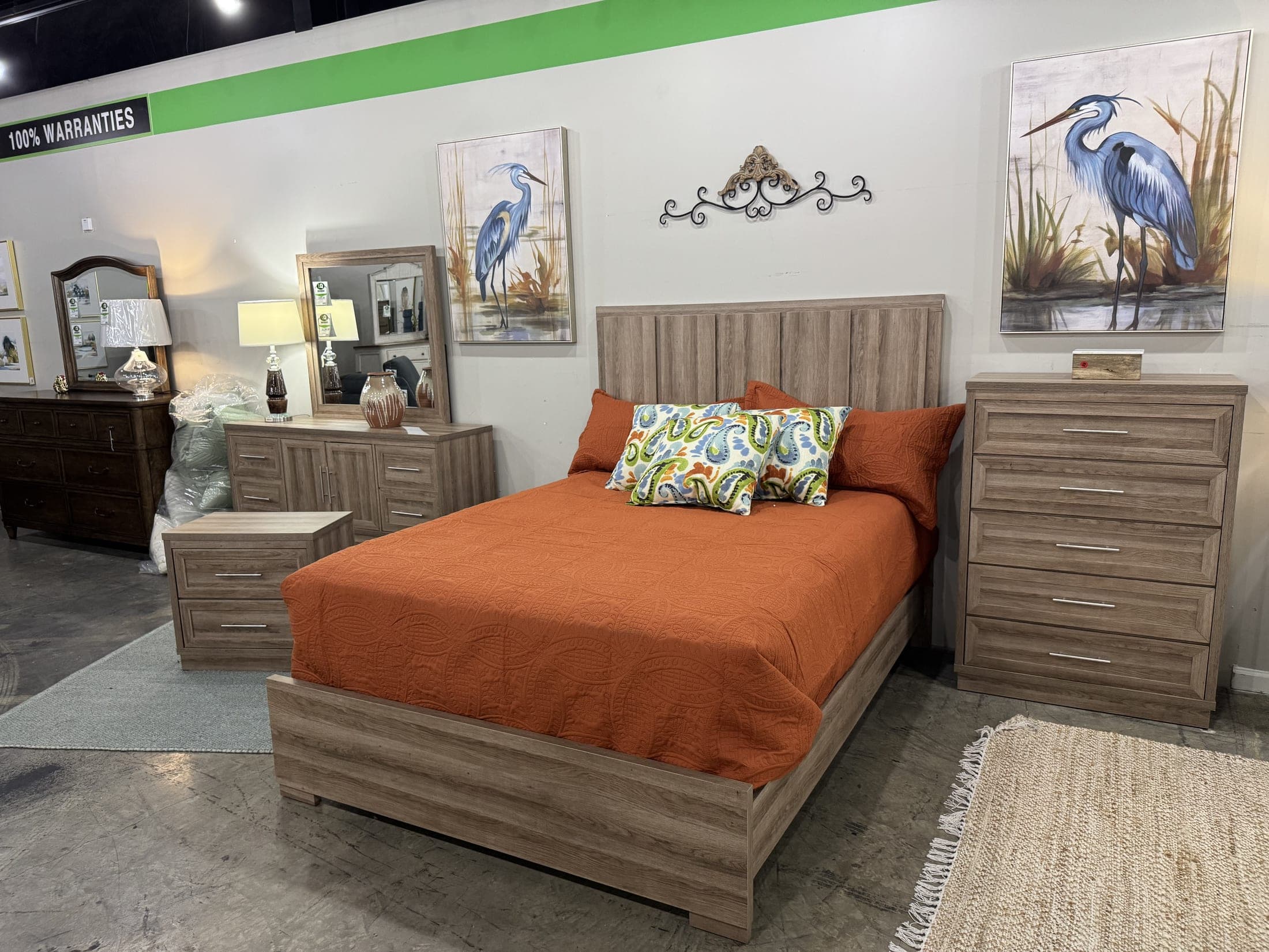 Bed made up in a burnt orange comforter beside a five-drawer chest on the LQ floor